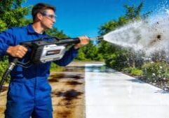 Pressure washing technician cleaning a concrete driveway, showcasing the effectiveness of professional driveway washing services | Envirowash